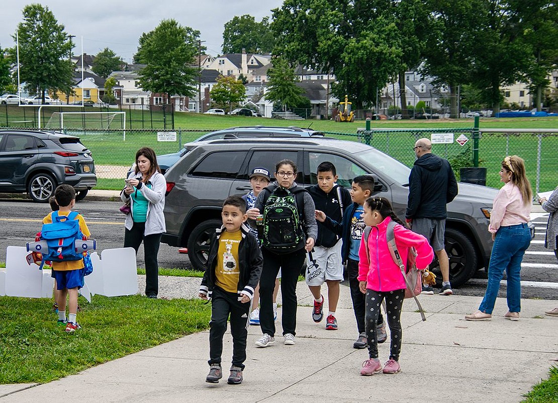 Students and their parents walk up to the doors of Park Avenue Elementary School just before 8:30 a.m. for the start of the second day of school. Some parents photograph their children in front of yard signs welcoming the students back.