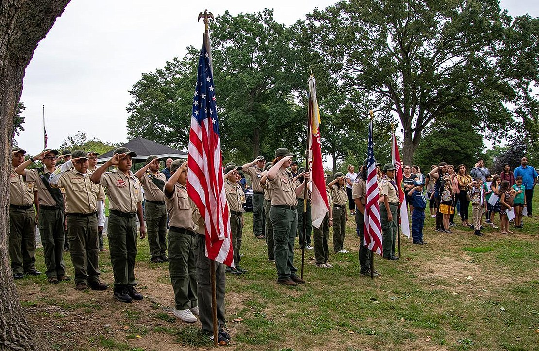 Boy Scouts and Girl Scouts from local troops salute during the National Anthem, sung by Annastasia Marcos.