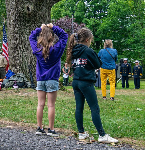 Eight-year-old twins Sophia and Chloe DeSouza watch the ceremony together, having traveled to Lyon Park with their family from their home on Francis Lane. Sophia wears a hoodie that bears the Rescue 40 logo, in reference to the Fire Patrol & Rescue company of the Port Chester Fire Department.