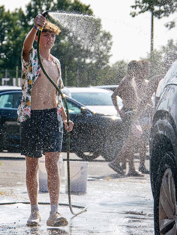 Hose in hand, junior midfielder Hudson McRedmond sprays cars as they pass him in the line, rinsing them off before they move on to the drying section.