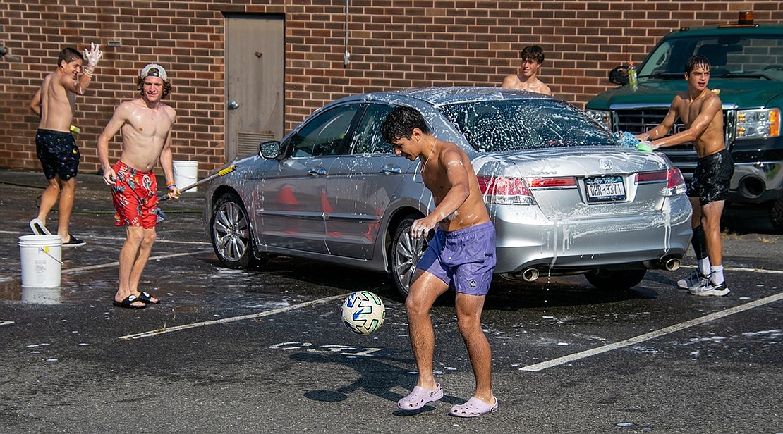 Blind Brook boys’ soccer junior midfielder Martin Otero juggles a soccer ball while his teammates wash a car behind him.