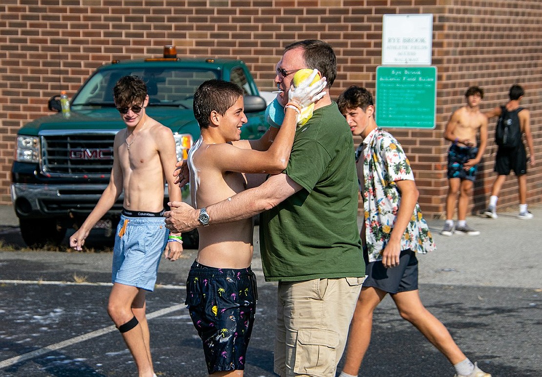 Senior midfielder Bryce Oling gives his father Scott a soapy hug as the team prepares to close down their event. He makes sure to squeeze the suds from both sponges he holds onto his father’s face and shoulders.