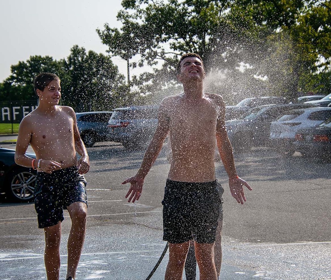 Getting covered in soapy water after washing cars for hours warrants a hose shower for Danny Wilk, a sophomore left wing. Senior midfielder Bryce Oling watches, waiting for his turn to get sprayed.