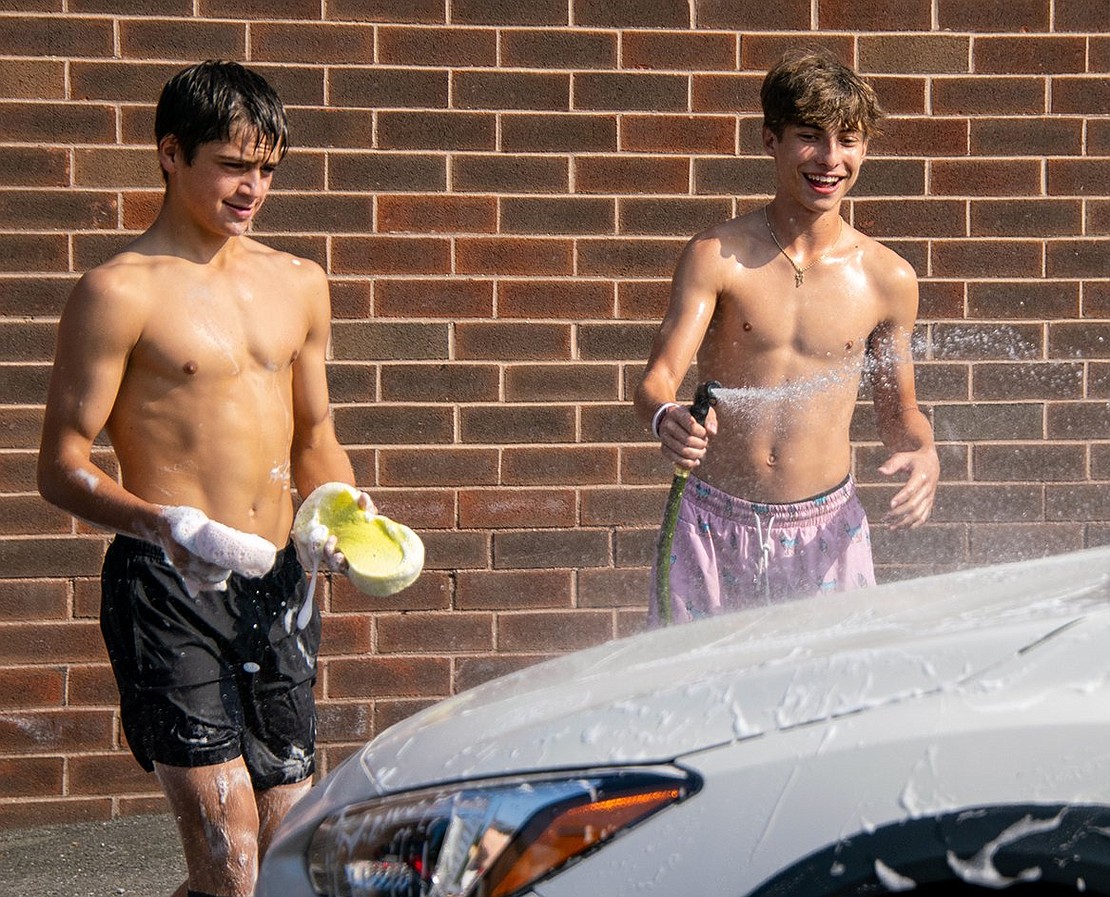 Midfielders Nico Gonzalez (left) and Michael Berman wash the hood of a car. The senior carries sponges while the junior wields a hose.