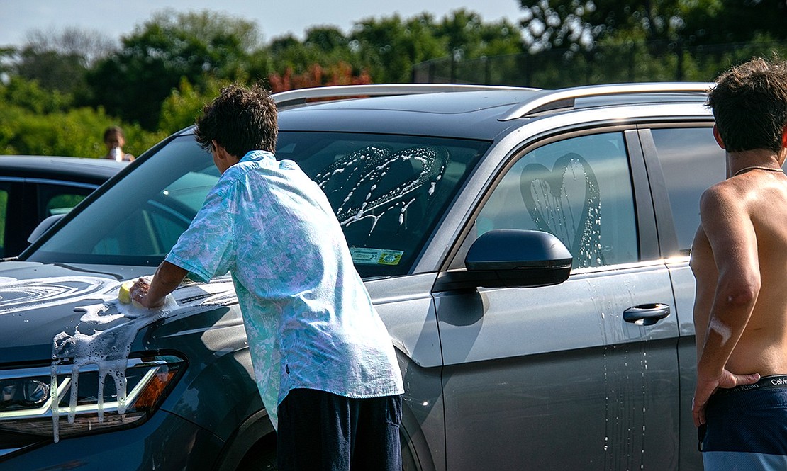 Luka Cuk, a sophomore goalie for the Blind Brook boys’ soccer team, washes the hood of an SUV he and other teammates—including senior goalie Jack Bachmann (right)—drew soapy hearts on. Beyond washing cars and raising funds for charity, the car wash was about community and team bonding.