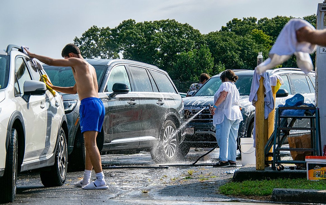 Equipped with multiple cloths, sophomore midfielder Henrique Almedia dries an SUV. Behind him, Holly Karetsky, mother of senior defenseman and captain Daniel, hoses down the tires of another SUV. Holly helped organize the event.