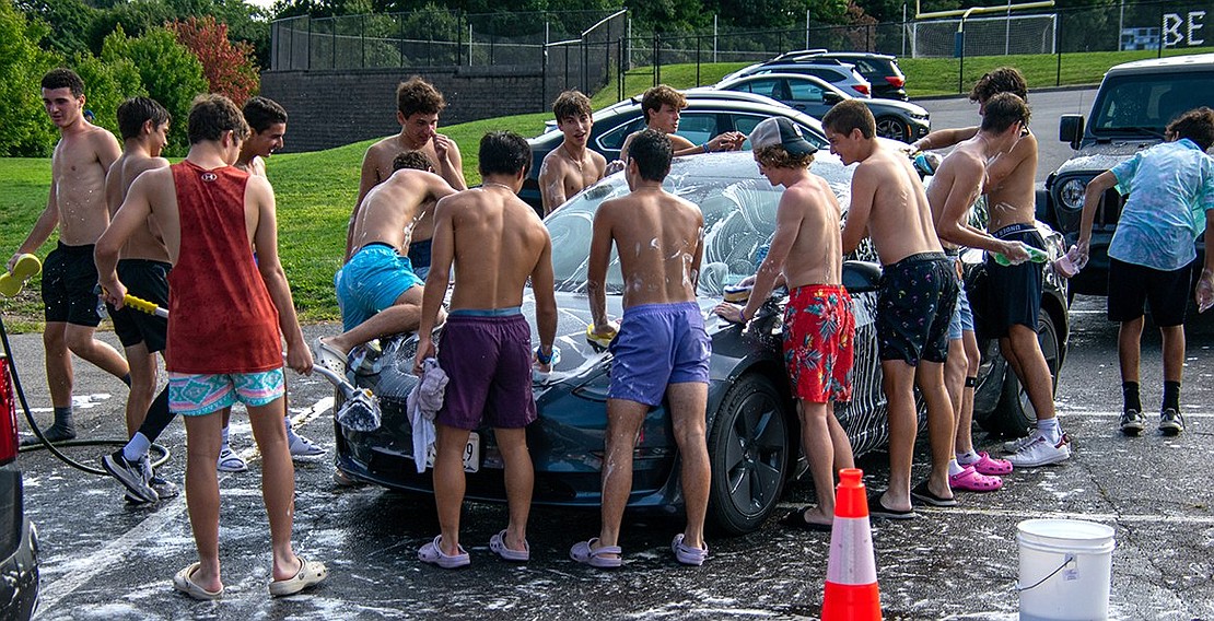 The Blind Brook boys’ varsity soccer team swarms a car that paid for a wash at their Saturday event. When people they knew entered the line with their cars, the boys would often sit on the hoods, play catch with sponges over the roof or draw shapes on the windows with suds.