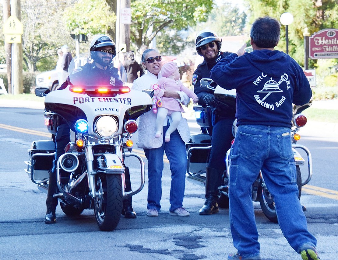 While watching outside of her Westchester Avenue apartment, Anita Pinoargotte gets up to take a photo by the parade-escorting Port Chester police officers with her 7-month-old granddaughter Fiona, who seems more interested in the motorcycles than the camera.