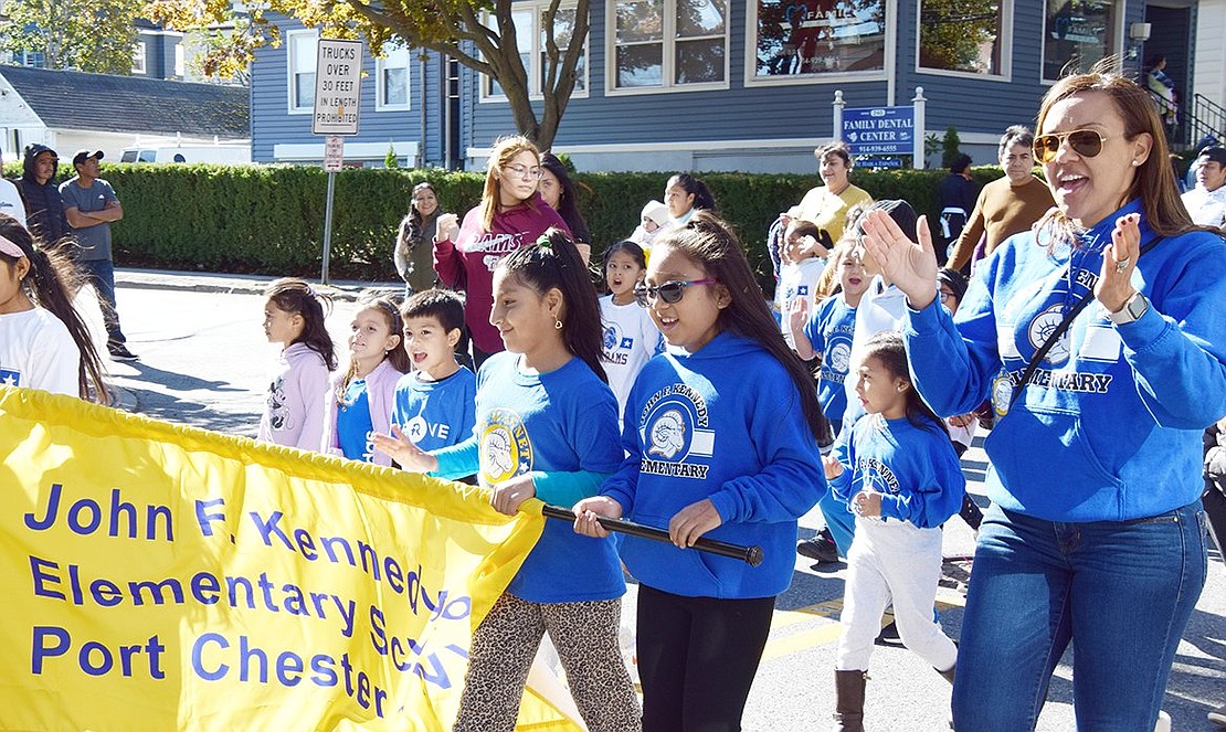 “JFK, JFK!” shouts John F. Kennedy Elementary School Principal Judy Diaz (right), leading the crowd through chants as she marches with her pupils.