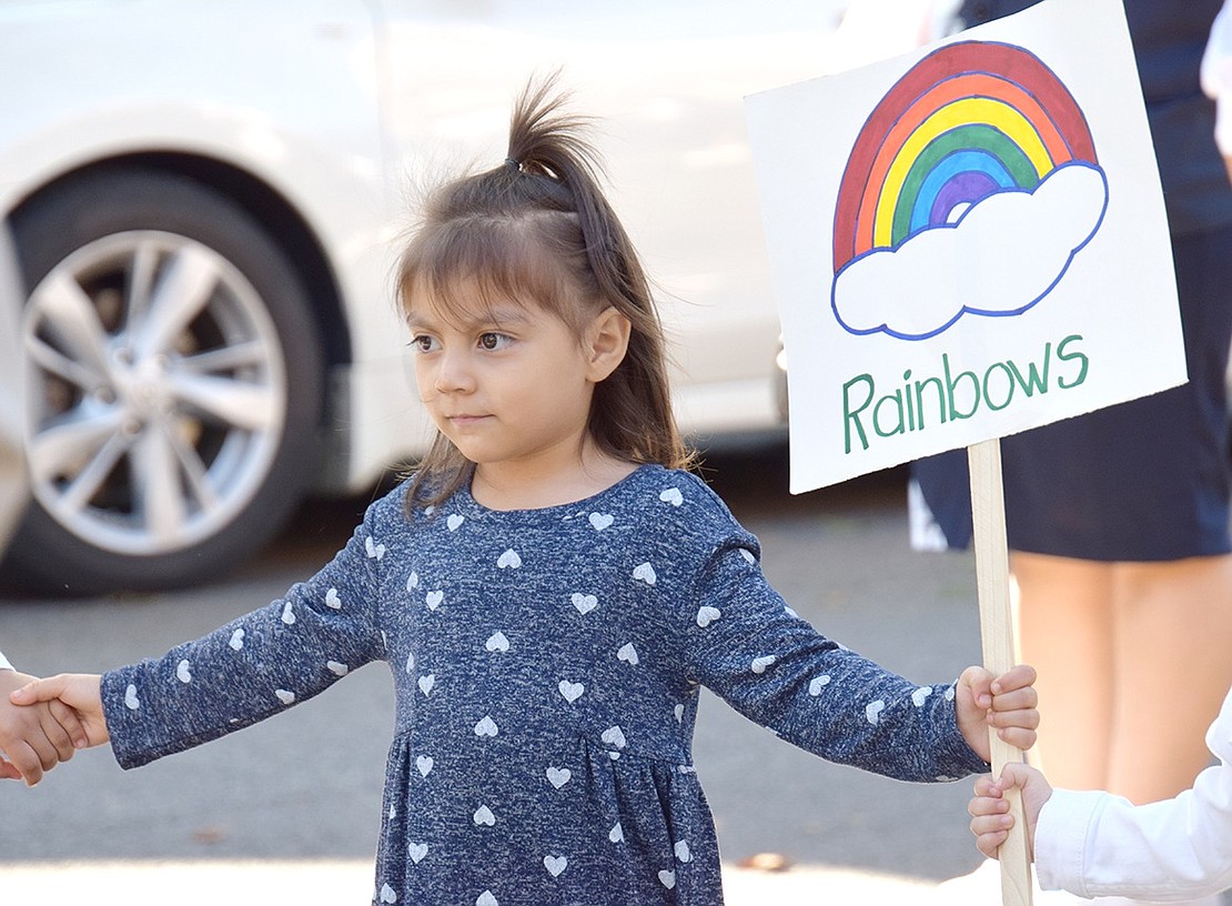 Hand-in-hand in a line of other young children marching with Segunda Iglesia Pentecostal Juan 3:16, Port Chester 3-year-old Estefania Alonzo proudly clutches a peaceful rainbow drawing to brandish.