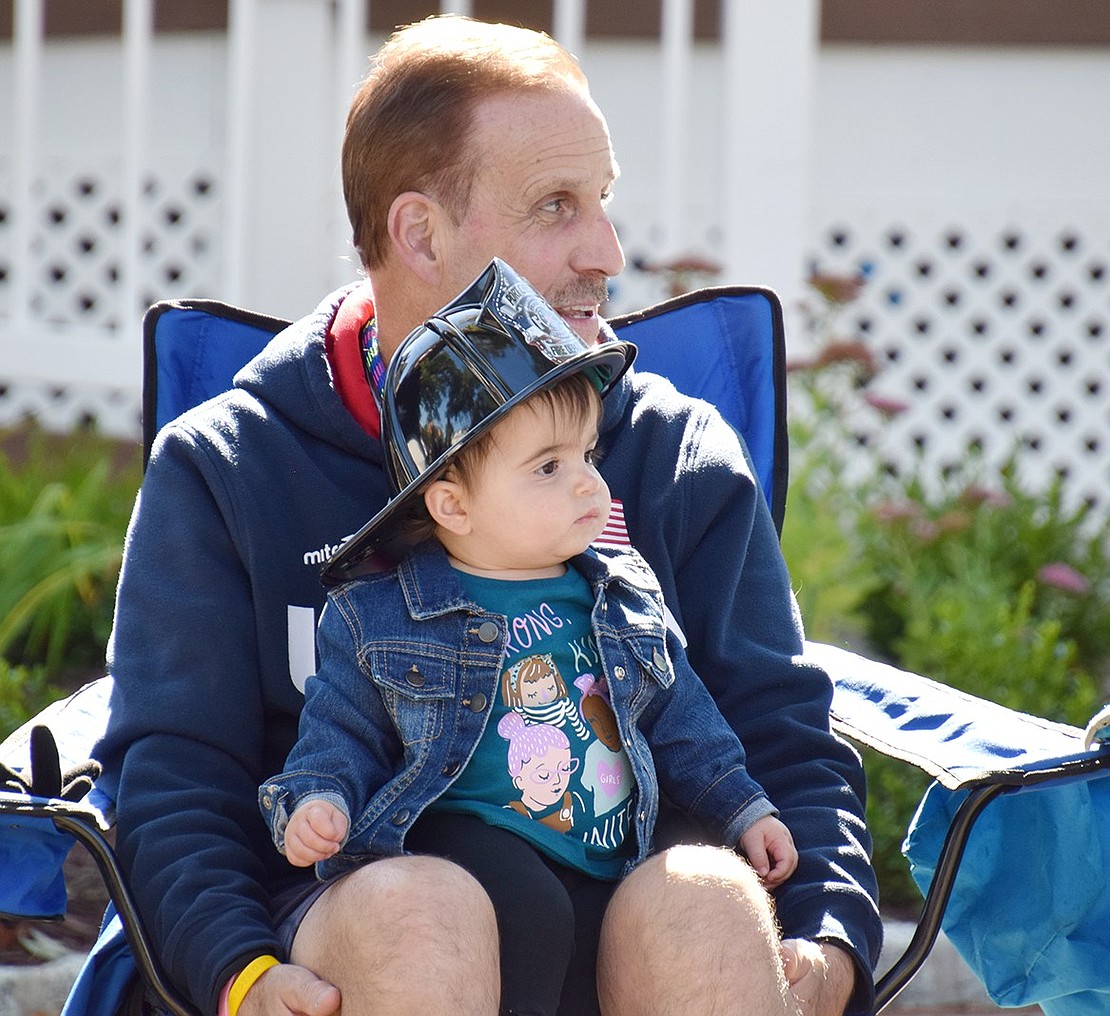 Thornwood resident Madelyn Nangle, 15 months old, makes herself effortlessly comfortable on her Port Chester grandfather Jim Florindi’s lap, giving herself a perfect seat to curiously watch the parade.