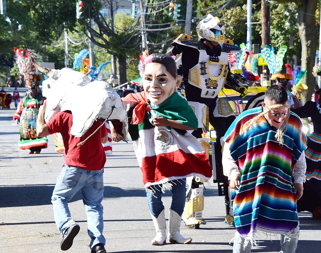 Marchers in festive costumes and attire join a giant robot and a bull to bring a fun, controlled chaos to the procession while trailing the Forastero DJ truck.