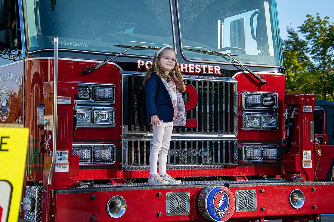 Mila Cammarano, a kindergartener, poses on the front of a Port Chester Fire Department truck from the Harry Howard Hook & Ladder Company.