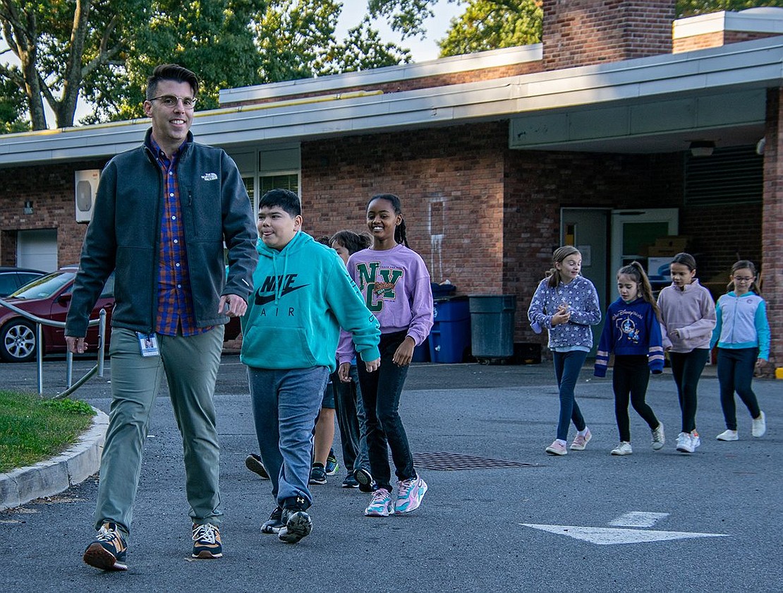 Anthony Travaglini, a technology and enrichment teacher at King Street Elementary School, leads a parade around the parking lot with his students.