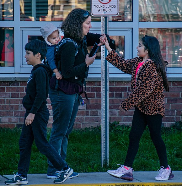 Fourth-grader Emma Weinstein high-fives Marissa Torento-Butkiewicz, a school parent and a local Girl Scout troop leader, as Weinstein parades around the parking lot with her classmates.