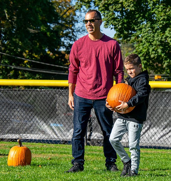 Luke Petriello found the perfect pumpkin, but the fruits are heavy. The King Street Elementary School third-grader hoists it to his chest and walks it back to his family while his father Tom trails behind.