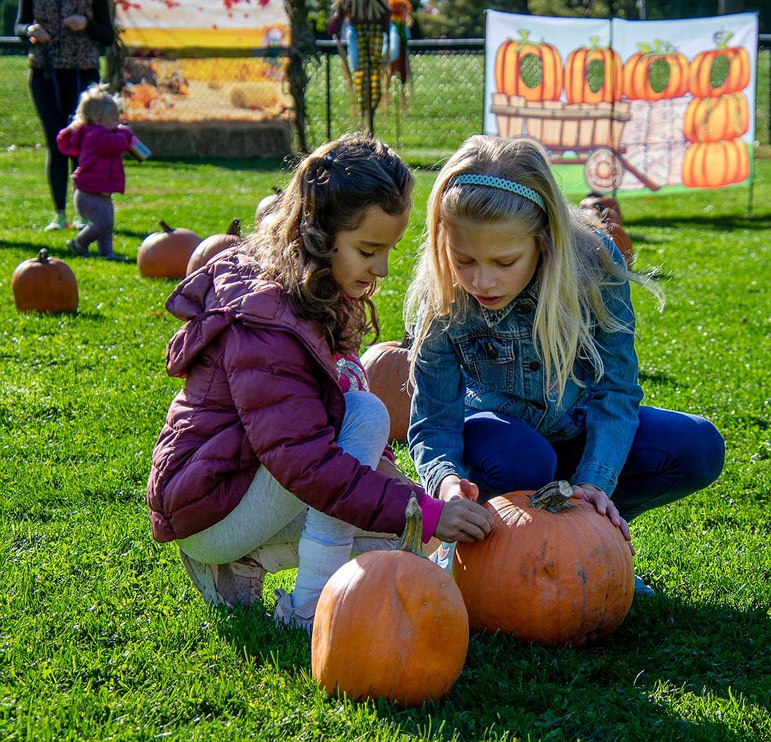 Alessandra Herrera (left) and Beatrice Satkus examine pumpkins at the patch. The Ridge Street School second-graders want to pick the perfect ones to adorn and potentially enter into the Village’s decorating/carving contest.