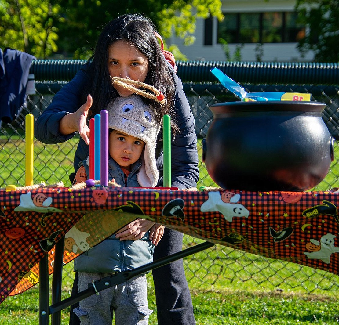 Valley Terrace resident Fany Nayi helps her 3-year-old son Niam toss rings for a game set up at the Pumpkin Patch.