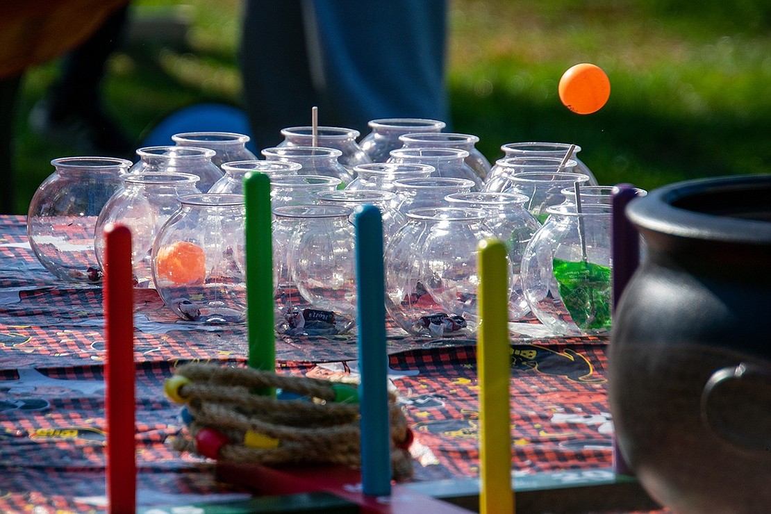 An orange ping-pong ball hovers over a set of small fish-bowl vases after it’s tossed by a Pumpkin Patch patron.