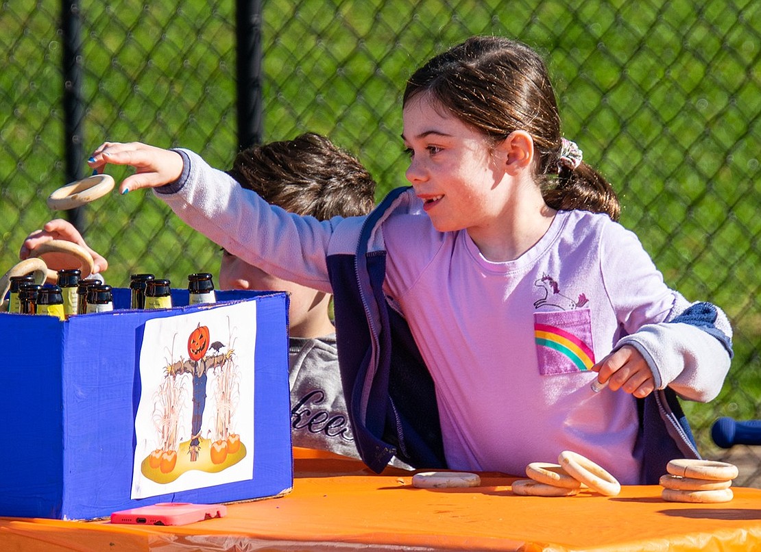 Showing off her skills, Ridge Street Elementary School second-grader Taylor Cirillo tosses a ring onto bottles.