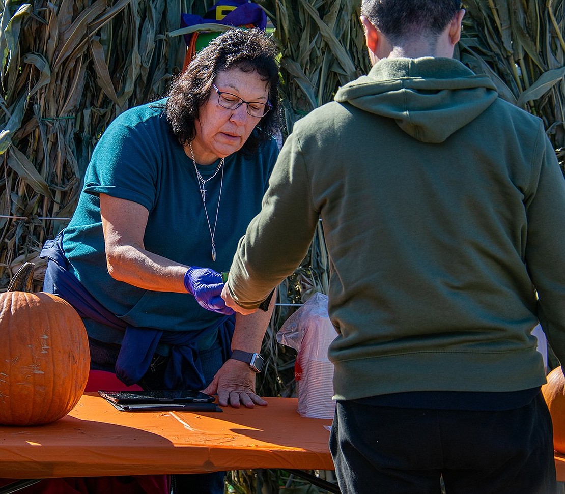 Janice Kunicki, Rye Brook’s senior recreation leader, collects payment for attendees’ pumpkins after they ventured into the field at Pine Ridge Park to select their ideal squash.