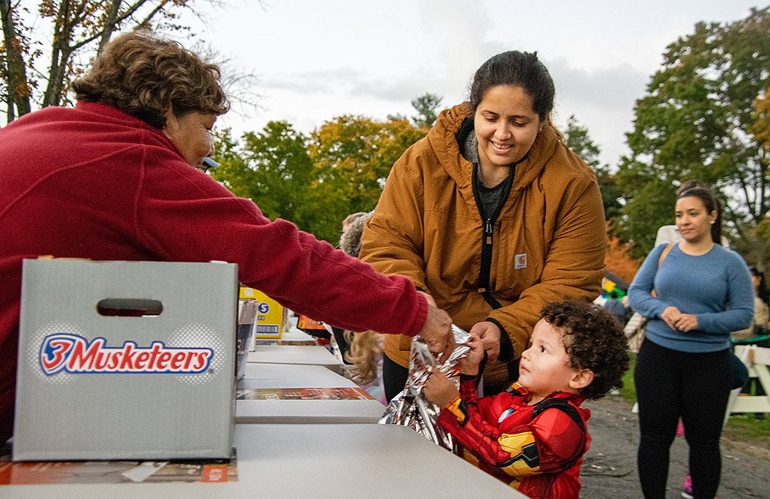 Two-year-old Emmanuel Garcia’s mother Mary Torres helps him accept candy for his trick-or-treat bag. The young Locust Avenue resident dressed up as Iron Man for the Port Chester Recreation Department-sponsored Halloween in the Park at Lyon Park on Wednesday, Oct. 26.