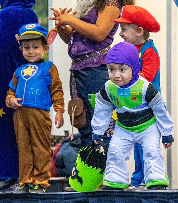 Jadiel Sigua, 2, is dressed as Buzz Lightyear this Halloween. He strikes a pose on stage for his family, all from Poningo Street, during a runway showcase.