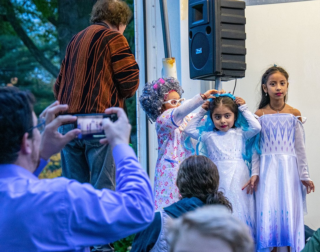 Queens and a grandma from Hillcrest Avenue unite for Halloween! Genesis Delcid, 6, helps Fernanda Rodan, 5, pin a wig to her hair so she can look like Elsa from Frozen. Beside them is 7-year-old Victoria Martinez, who also dresses as Elsa.