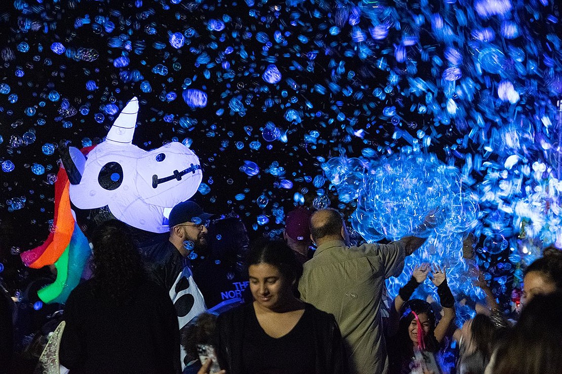 Francis Lane resident George Samaras dons a large unicorn blow-up head as he and his family dance in a shower of shimmering bubbles, backlit by ultraviolet lights.