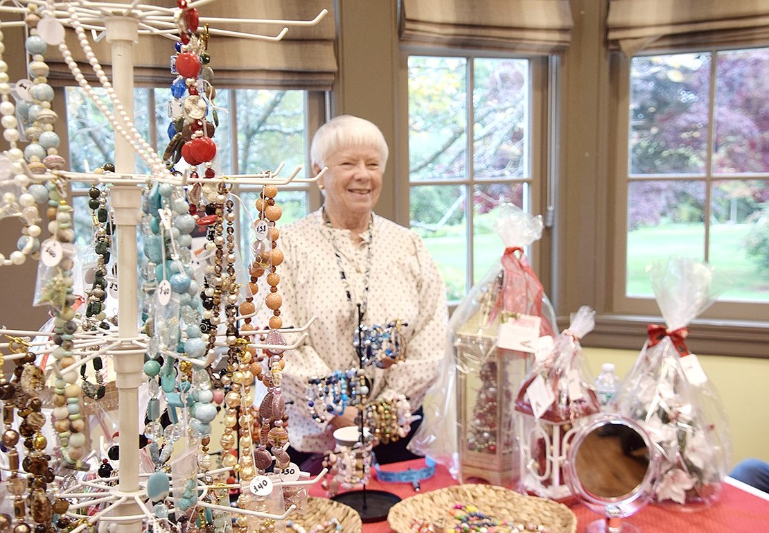 A first-time artist presenting her work at the ART10573 exhibition, Port Chester’s Kathy Dreves attends to her booth filled with vibrant jewelry pieces and ornate holiday adornments.