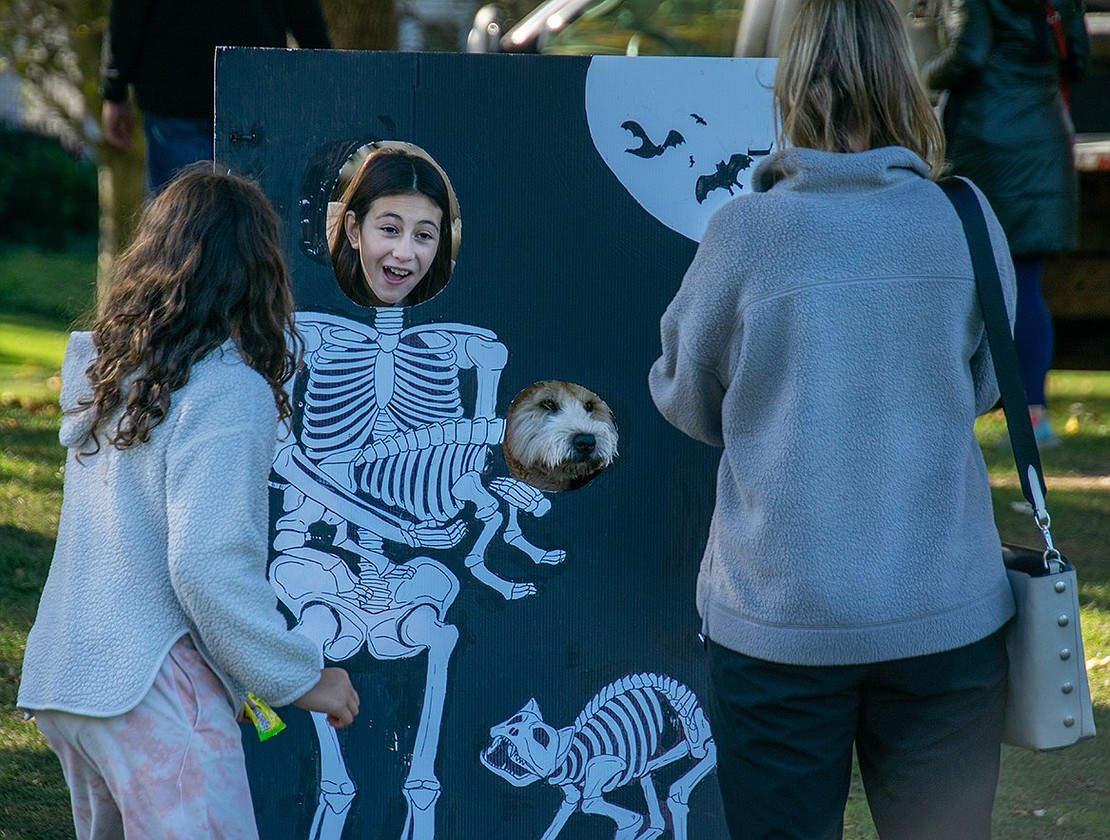 Blind Brook Middle School seventh-grader Gabby Gonzalez poses in a Halloween-themed cutout with 1-year-old Wheaton terrier Lulu, her family’s dog. Gabby’s sister Saralina, a Ridge Street Elementary School fifth-grader, watches while their mom Stacy takes a picture.