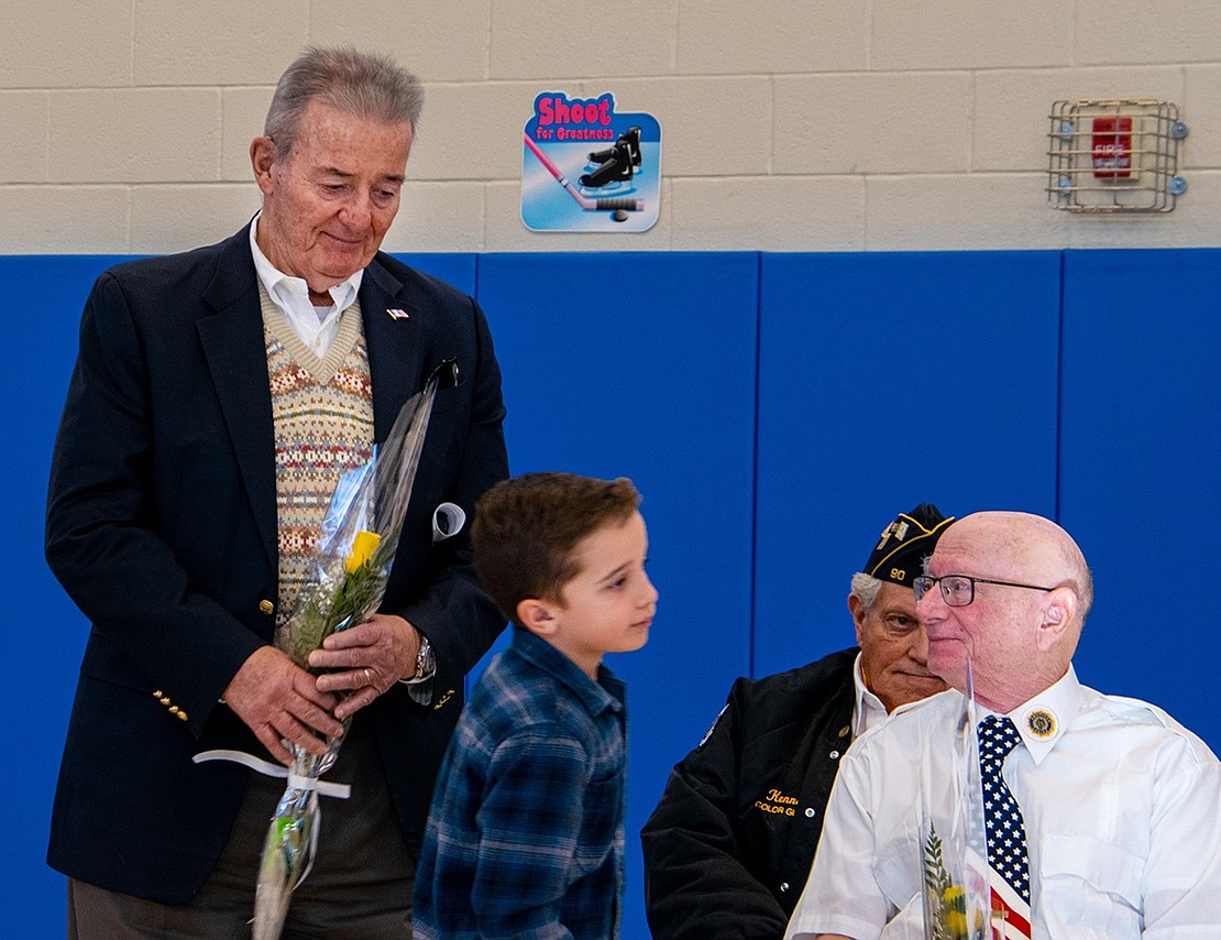 West Harrison resident Tom Dushas watches with pride as his grand-nephew Luke Petriello, a third-grader, thanks other veterans for their service after handing his uncle a rose. Dushas served in the U.S. Army.
