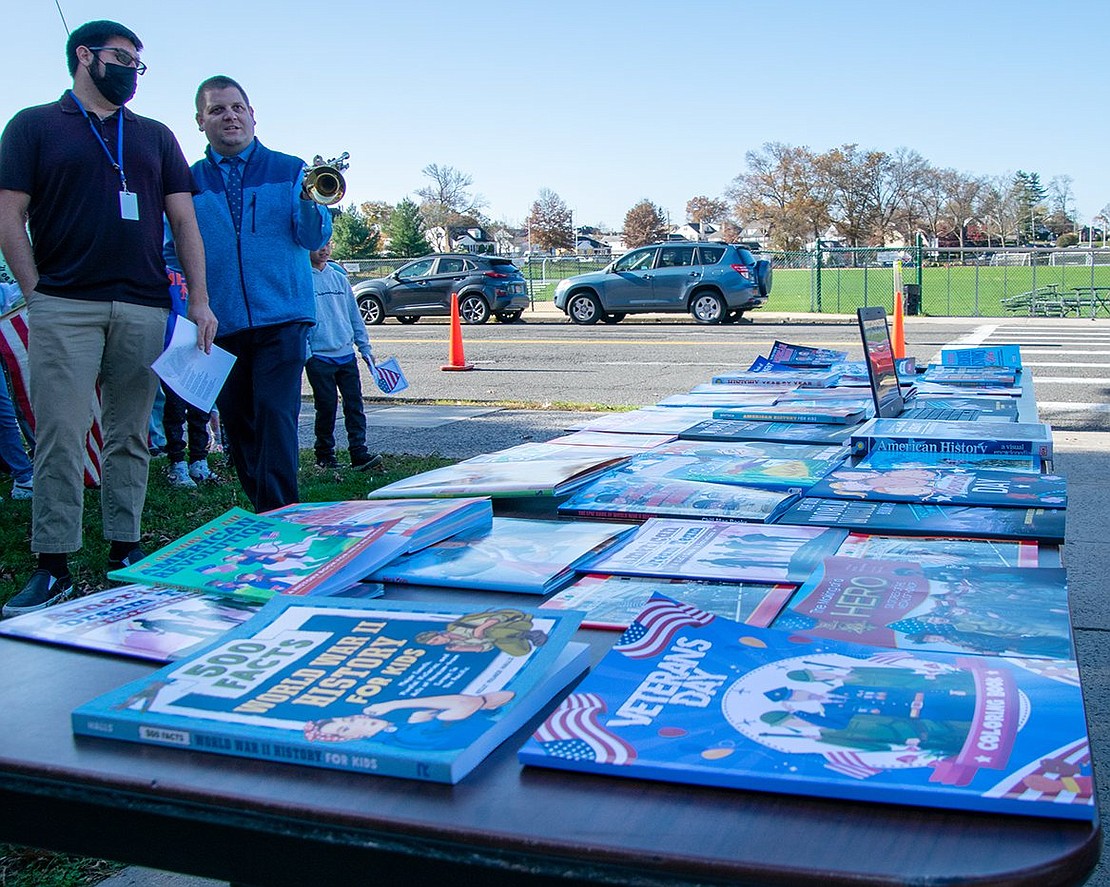 Park Avenue Elementary School faculty members discuss the table full of donated Veterans Day-themed books before the ceremony starts. The books were donated by two retired Port Chester social studies teachers, Isabel and Hank Birdsall.
