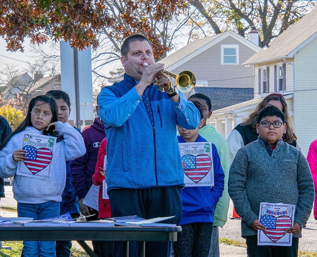 Michael Johnson plays Taps at Park Avenue Elementary School, concluding the ceremony. The music teacher’s students stand behind him, holding American flags in the shape of hearts.