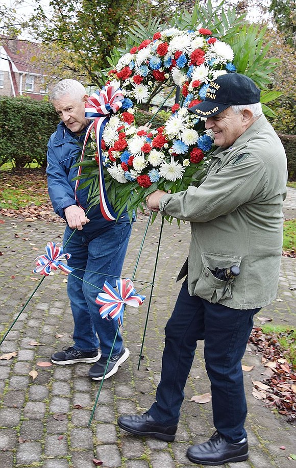 Port Chester veterans Pat Barrese (left) and Dominick Mancuso walk a memorial wreath over to the flagpole monument recognizing local veterans who died during World War II and the Korean War, with a special memorial for the 8 Willow Street Boys who gave their lives in WWII.