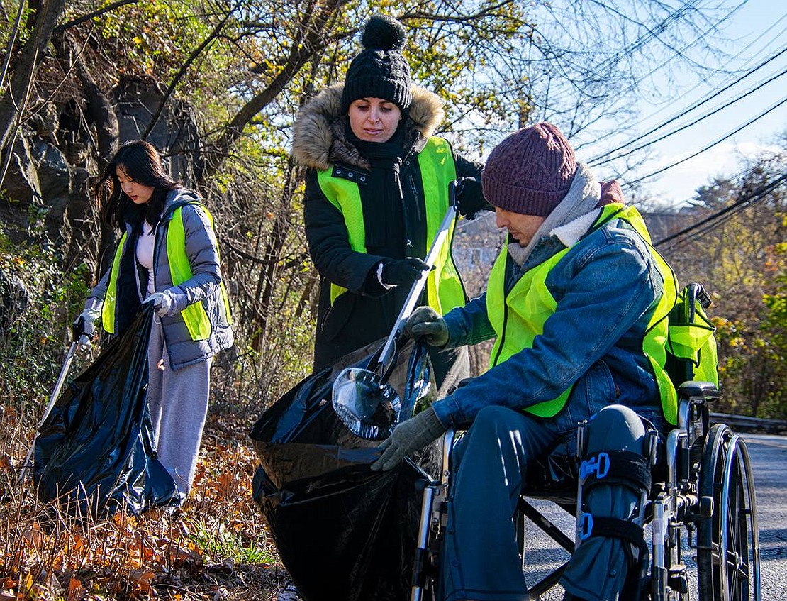 Rye Brook Sustainability Committee President Briggitte Dix places a foil plate into a garbage bag her husband Wesley Calvin holds open. Behind the Osborne Place residents, Blind Brook High School junior Lana Kim collects garbage in a bag of her own.