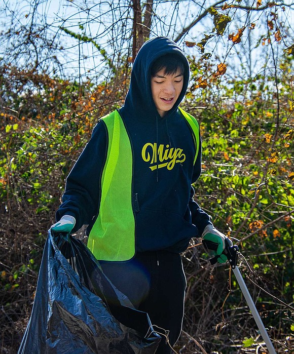 Taka Kimura, a junior at Blind Brook High School, hoists a garbage back full of trash he collected around Bowman Avenue.