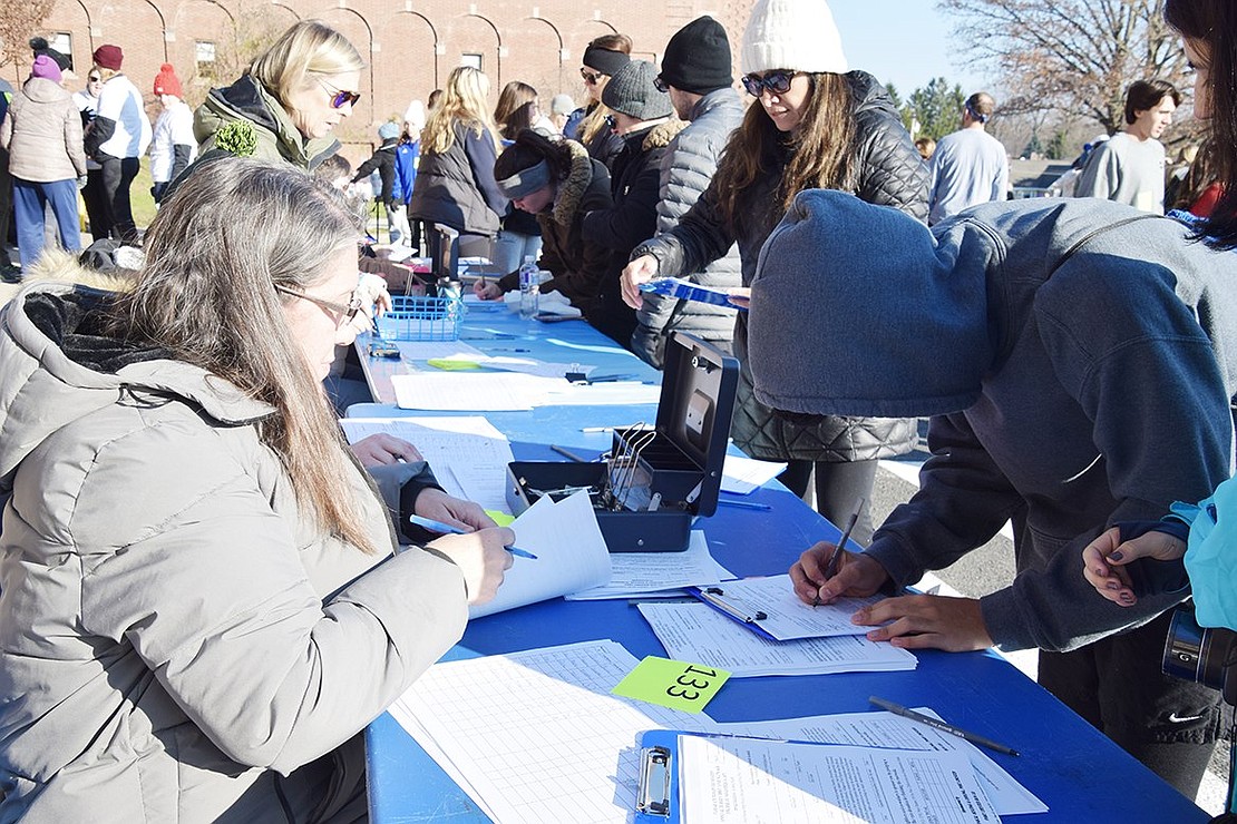All but 74 of the 228 people who participated in the Turkey Trot signed up the morning of the run/walk. TTF volunteer Renée Carlucci helps a runner with the registration process. Liz Rotfeld chaired the event for the second year.
