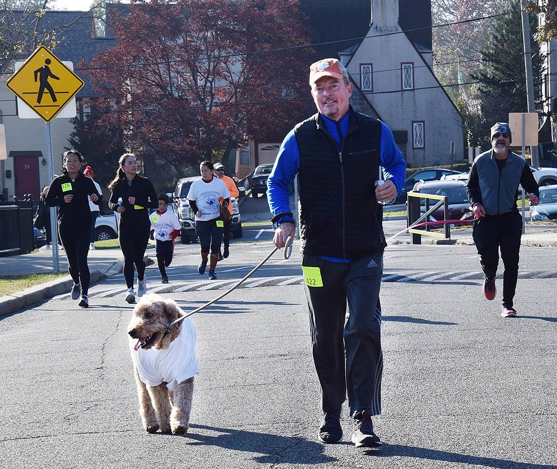 Blake Kerrick of Valley Terrace was among the many participants who kept pace with their dogs. His frisky golden doodle Toby accompanies him along the course. Behind him is David Hartman of Argyle Road with his dog Scout (hidden). Scout and Hartman’s previous dog have been trotting along with him in the Thanksgiving run every year since 2014.