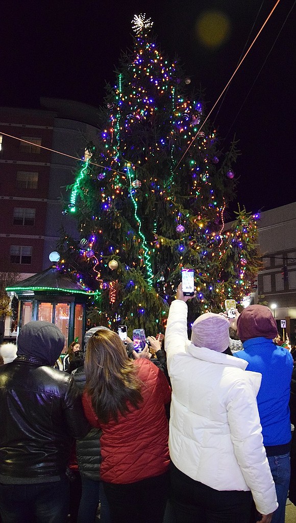 Once the tree is lit, people take photos of the 26-foot evergreen, which was donated by Rosa Cajamarca and Fernando Uyaguar of 9 Tower Hill Dr.