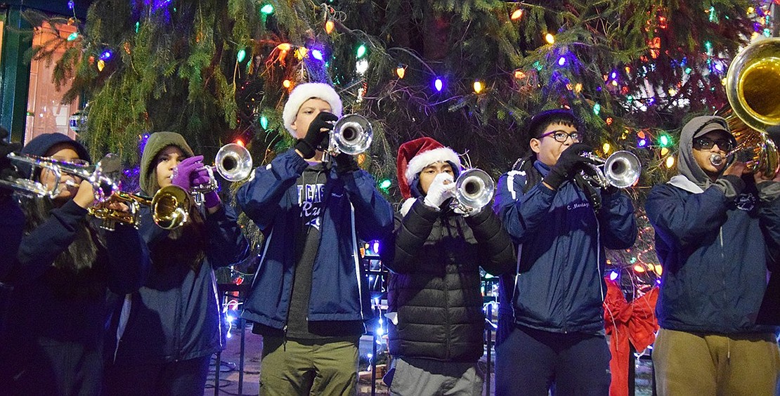 Trumpeters and tuba players in the Port Chester High School Band raise their instruments to play “We Wish You a Merry Christmas” in front of the lit Christmas tree.