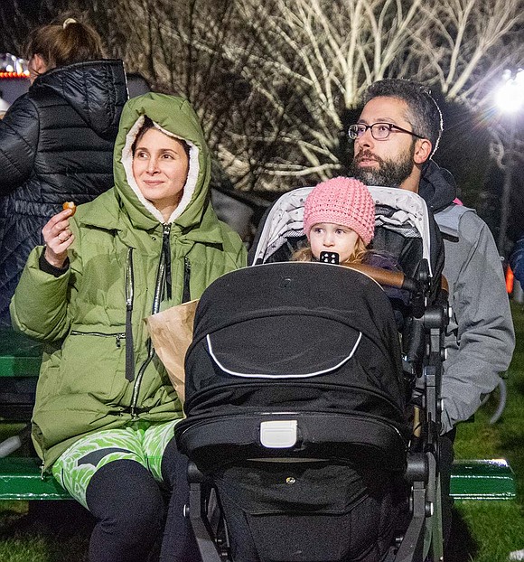 Beacon Lane residents Aliza and Boris Zubov sit with their 2-year-old daughter Juliette as they watch members of the Port Chester High School Band perform holiday tunes.