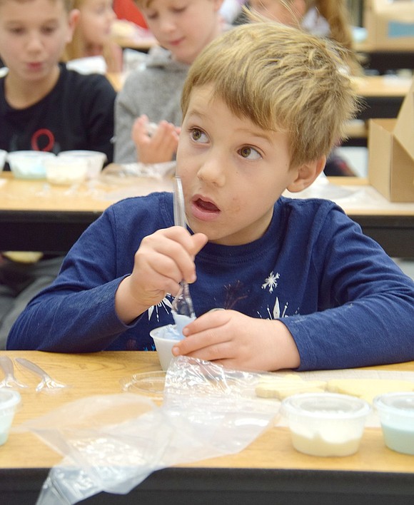 Kindergartener Charlie Liebenstein stirs his frosting carefully to find the perfect not too hard, not too runny consistency.