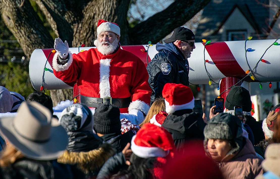 Santa Claus, who also goes by the name Charlie Sacco, waves to the crowd gathered at Lyon Park following the annual Christmas Parade down King Street on Saturday, Dec. 10. With him are members of the Port Chester Fire and Police departments, who toss candy canes to eager children ready to partake in the Santa in the Park event that followed the procession.