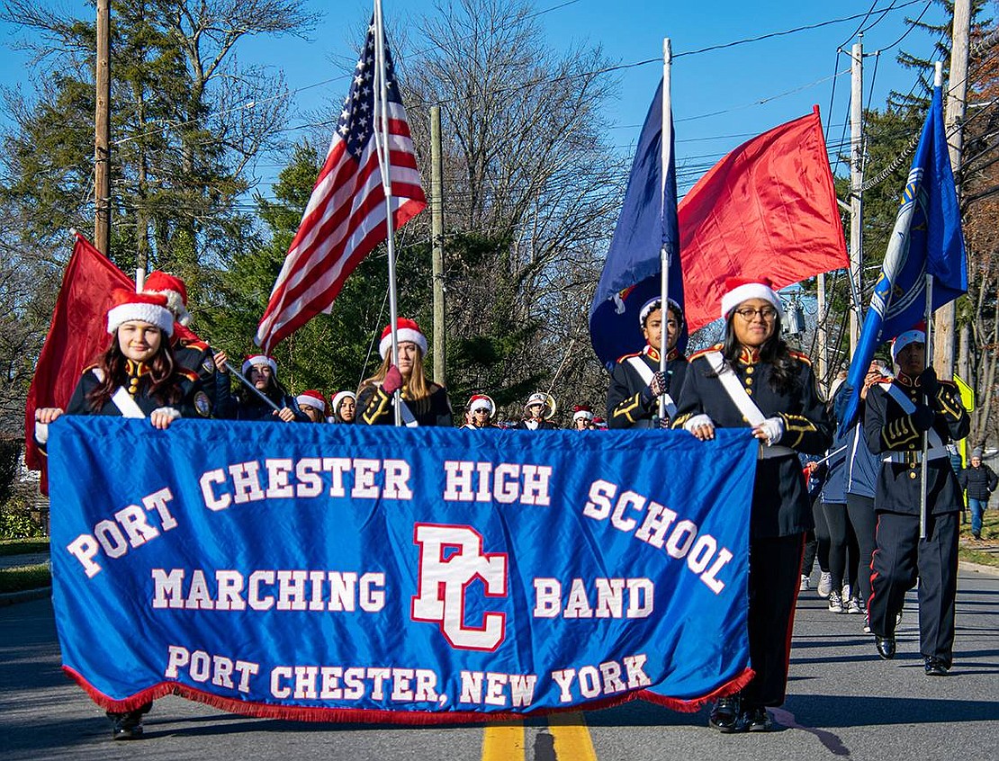 Members of the Port Chester High School Marching Band carry the performing troop’s banner as they lead the Christmas Parade down King Street.