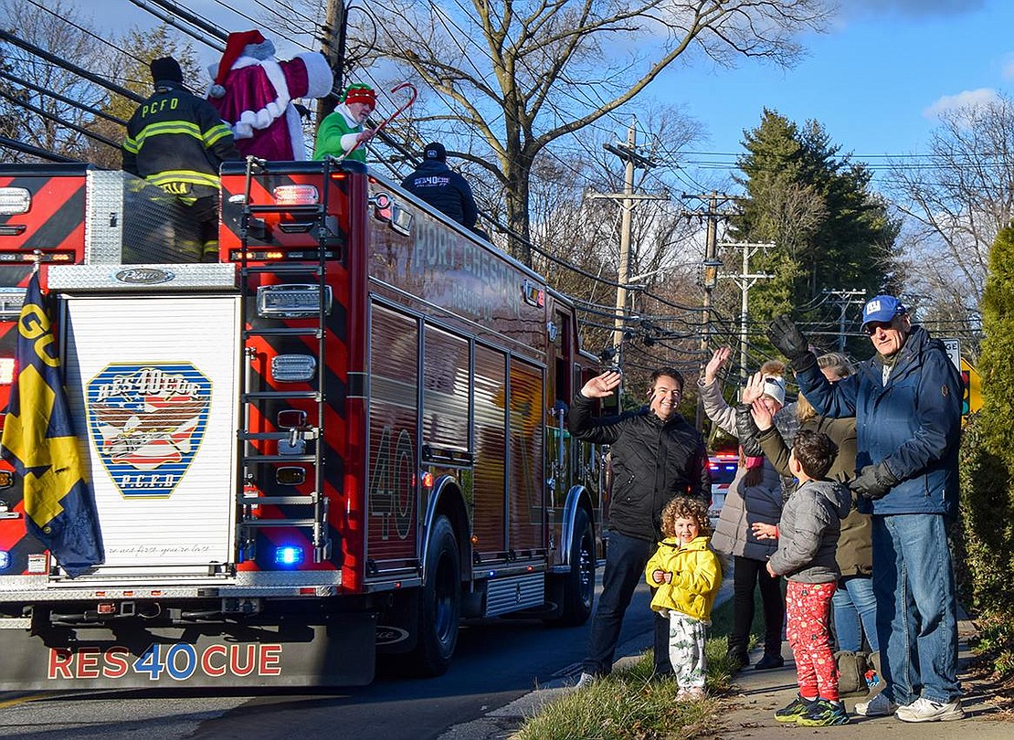 The Bell and Krebs families, all residents of Valley Terrace, wave to Old Saint Nicholas as he passes by on a Port Chester fire engine traveling down North Ridge Street during the Port Chester and Rye Brook fire departments’ annual Santa Run on Sunday, Dec. 18.