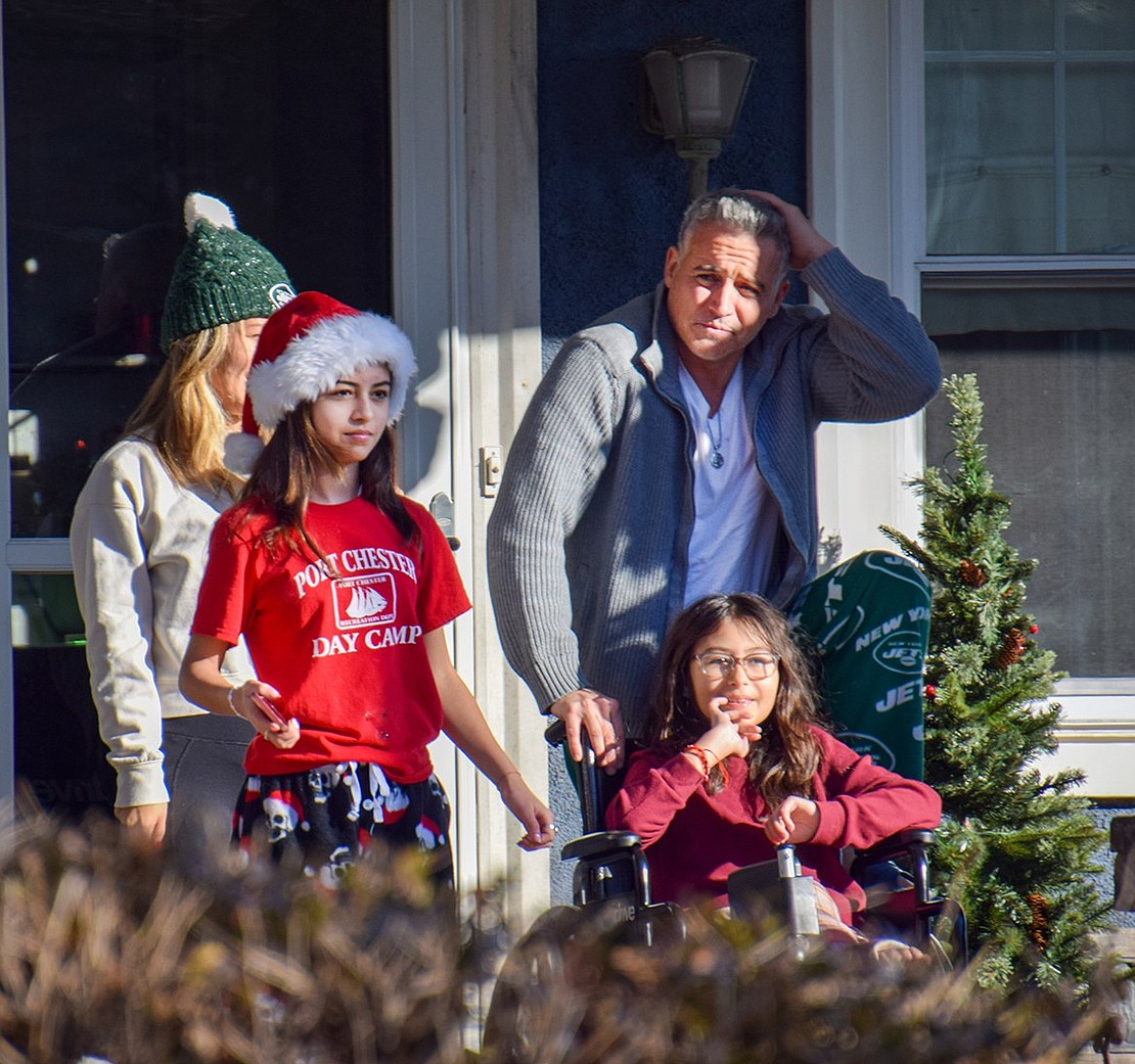 Ariana (left), 12, and Kylie O’Meara, 10, watch Santa pass their Putnam Avenue residence in a parade of fire engines with their parents Liz and Barry.