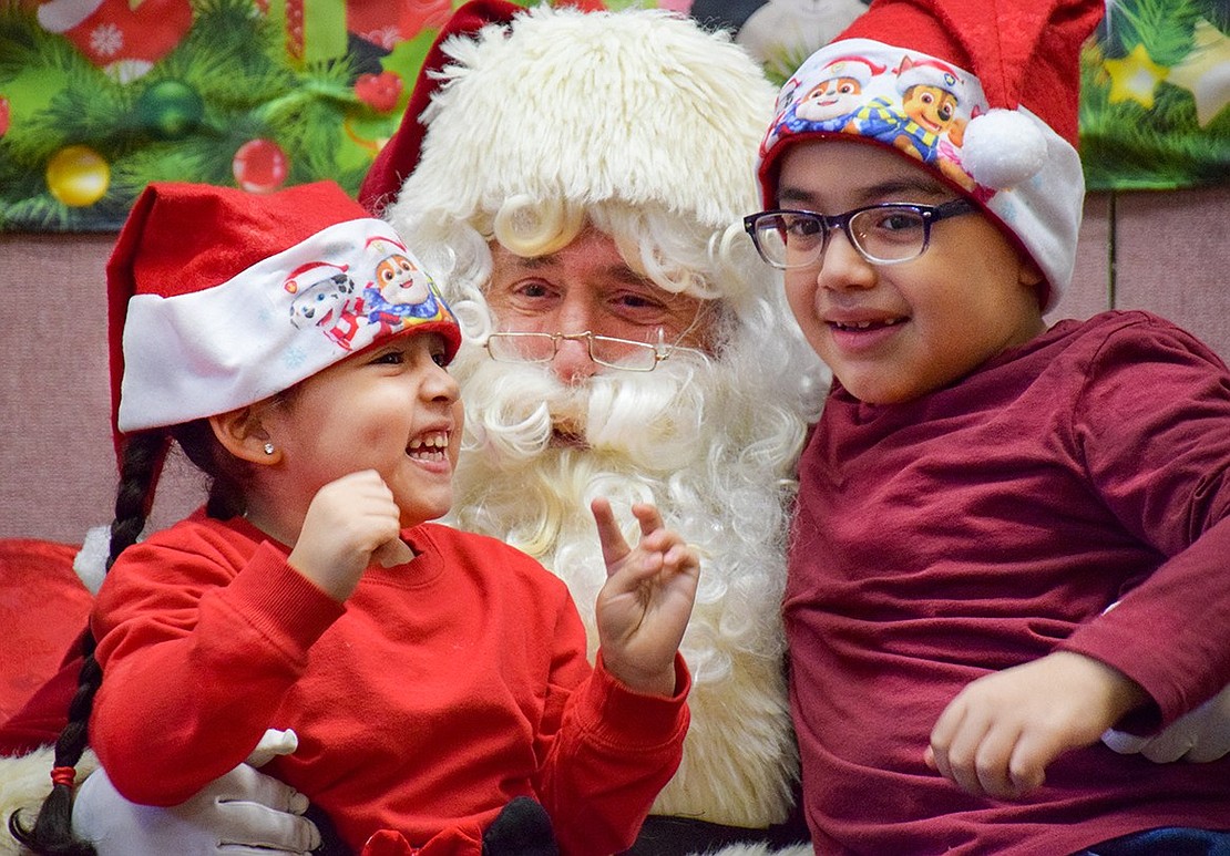 Kathleen Pacheco, 4, grins in glee as she meets Santa—who also goes by John Mecca—with her 8-year-old brother Jeremy. The Locust Avenue residents attended the Breakfast with Santa event at the Don Bosco Community Center on Saturday, Dec. 17.