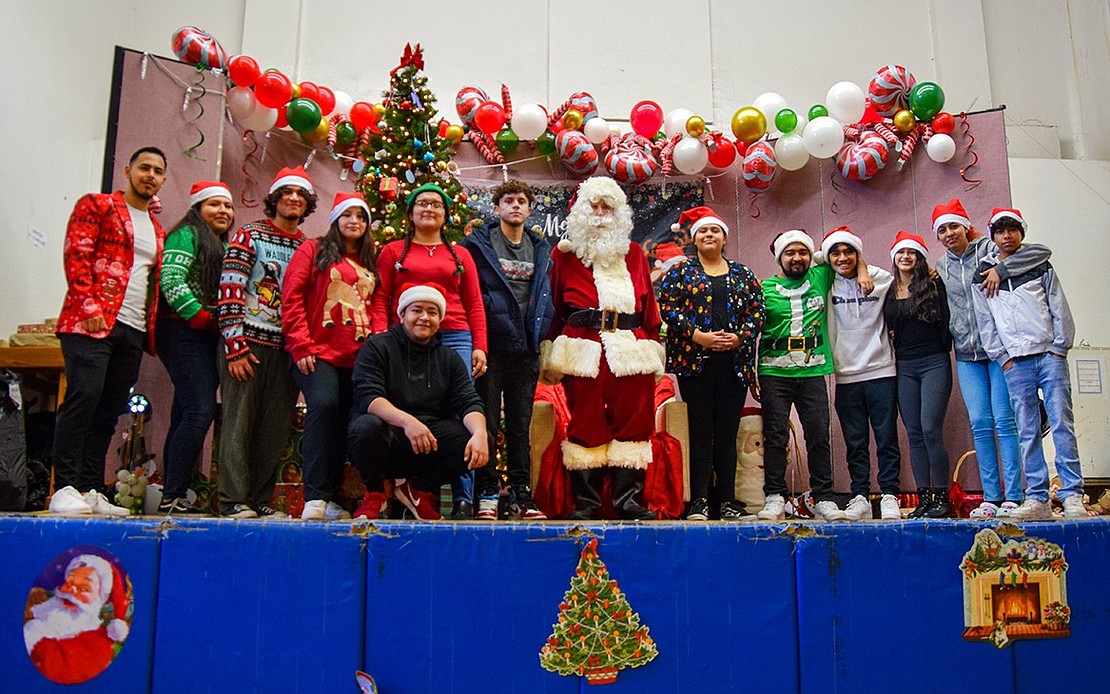 Santa poses with his elf helpers, many of whom are Port Chester High School graduates.