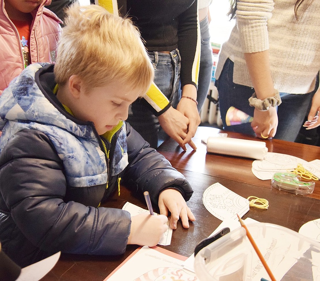 Owen Kronforest, 5, of North Regent Street uses colored pencils to decorate a paper Christmas tree ornament.